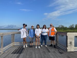 People standing on dock by water, enjoying scenic view.